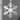 Silver metal snowflake Christmas wall ornament on a living room wall above a sofa, with soft winter light.