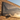 Metal airplane wall art hanging on a brick wall at sunset, casting sharp shadows