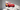 Red metal Lightning McQueen silhouette wall art mounted above a child's bed in a modern bedroom