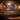 Metal tattoo shop sign hanging on a brick wall in a dimly lit man cave