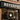 Tattoo shop storefront with a custom metal sign casting shadows on brick
