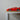 Side view of a red toy race car displayed on a wooden shelf indoors.