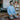 A young man in a striped shirt kneeling in prayer on a rug in a cozy living room setting.